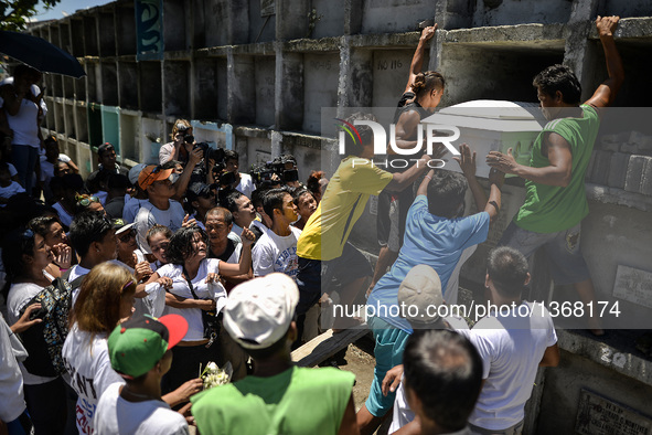 The coffin of a suspected drug pusher and victim of a vigilante-style execution is placed on a tomb as relatives grieve during a burial cere...