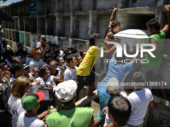 The coffin of a suspected drug pusher and victim of a vigilante-style execution is placed on a tomb as relatives grieve during a burial cere...