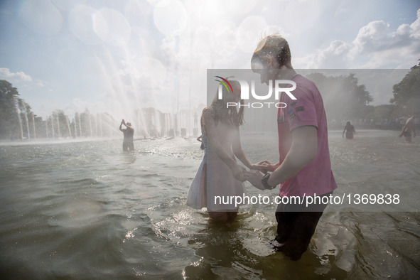 A couple hold hands while standing in a fountain in Moscow, Russia, on Aug. 2, 2016.