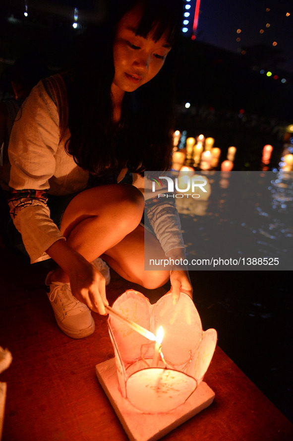 A tourist lights a lantern during a traditional lantern fair in Ziyuan County, south China's Guangxi Zhuang Autonomous Region, Aug. 16, 2016...