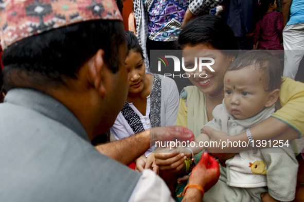 A Nepalese priest ties a sacred thread to a child during Janai Purnima Festival at Lalitpur, Nepal, Aug. 18, 2016. Janai Purnima, also known...