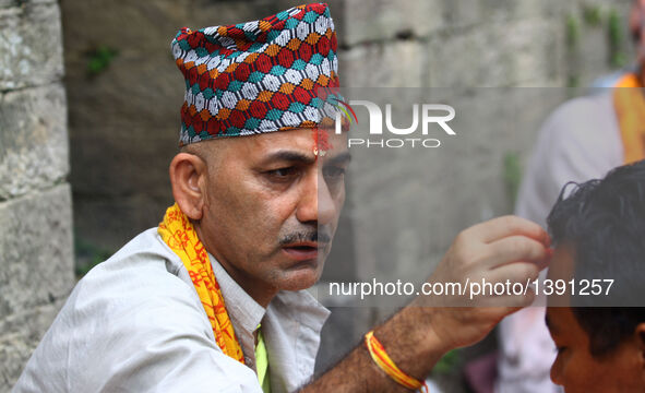 A Hindu priest offers tika, coloured powder and rice used as a blessing, to a devotee during the Janai Purnima Festival in Kathmandu, Nepal,...