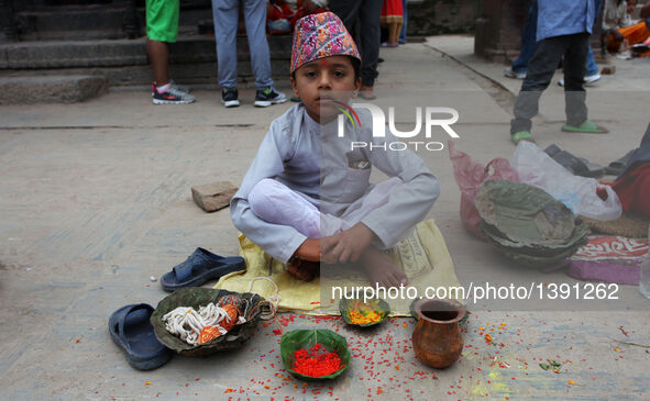 A young Hindu Brahmin priest waits for devotees to tie sacred thread during the Janai Purnima Festival in Kathmandu, Nepal, Aug. 18, 2016. J...