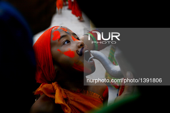 A Nepalese boy wearing festive attire drinks milk while attending a parade of the Gaijatra festival, or the festival of cows, in Kathmandu,...