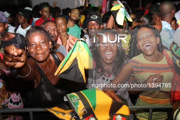 People celebrate Jamaican athletes winning the Olympic gold medal of the men's 4x100m relay event, in Kingston, Jamaica, Aug. 19, 2016.