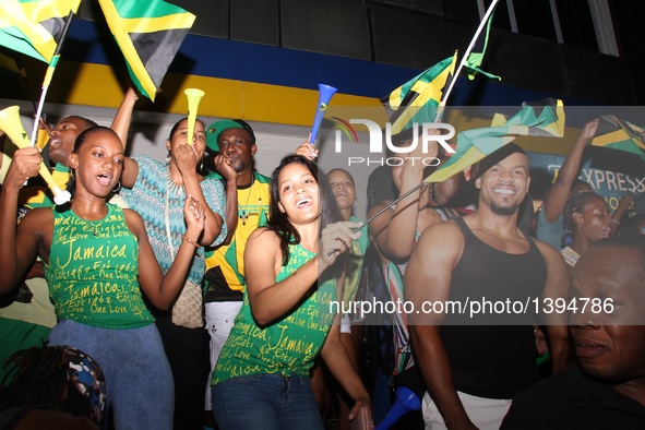 People celebrate Jamaican athletes winning the Olympic gold medal of the men's 4x100m relay event, in Kingston, Jamaica, Aug. 19, 2016.