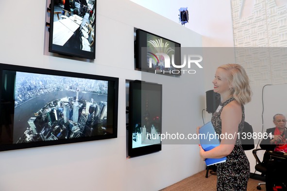 A visitor watches a photo show on China's Shanghai during a tourism promotion event in New York, the United States, Aug. 23, 2016. China's c...