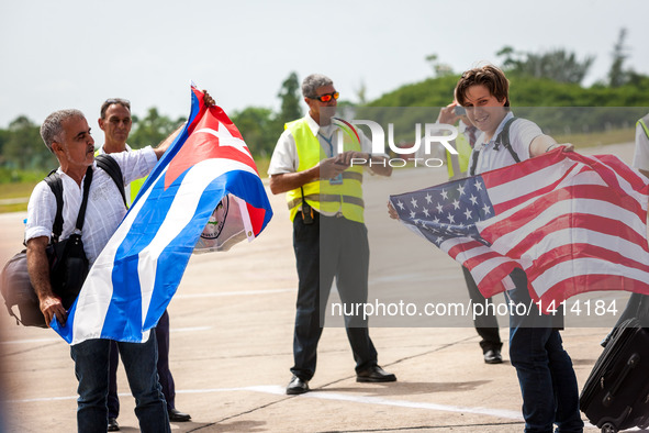 Passengers from the first commercial flight from U.S., pose for pictures with national flags of Cuba and the U.S., at the Abel Santamaria In...