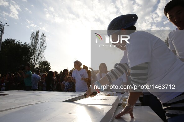 A baker cuts a cake at a park in Bishkek, Kyrgyzstan, Sept. 25, 2016. A cake measuring 1.5 tons and 100 square meters was prepared by a grou...