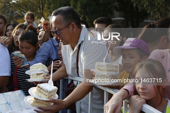 People buy cakes at a park in Bishkek, Kyrgyzstan, Sept. 25, 2016. A cake measuring 1.5 tons and 100 square meters was prepared by a group o...