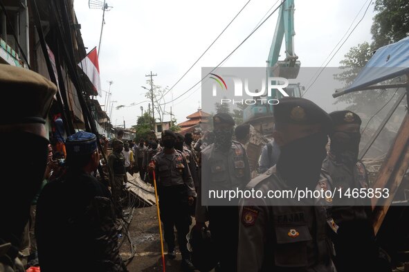 Police officers gather as an excavator demolishes houses at Bukit Duri, a slum area in Jakarta, Indonesia, Sept. 28, 2016. The Jakarta city...