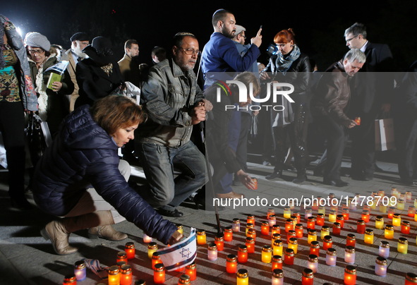 People lay candles in front of a monument during a ceremony commemorating the massacre of about 150,000 Nazi victims in Babi Yar near Kiev f...