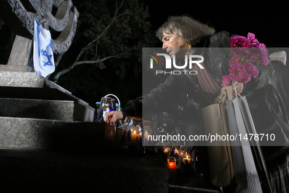 A woman lays a candle in front of a monument during a ceremony commemorating the massacre of about 150,000 Nazi victims in Babi Yar near Kie...