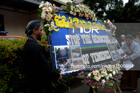 People bring bouquet of flowers and posters during a rally protesting airstrikes at a funeral hall in Yemen, in front of Saudi Arabian embas...