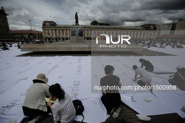 People sew white cloths with names of victims of the conflicts between the Revolutionary Armed Forces of Colombia (FARC) and the government,...