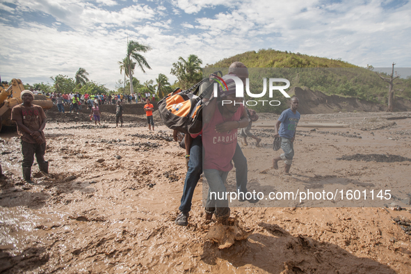 People walk to cross the river after hurricane Matthew washed away the bridge in Petit Goave, Haiti, on October 6, 2016. A main bridge on th...