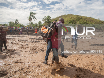 People walk to cross the river after hurricane Matthew washed away the bridge in Petit Goave, Haiti, on October 6, 2016. A main bridge on th...