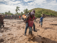 People walk to cross the river after hurricane Matthew washed away the bridge in Petit Goave, Haiti, on October 6, 2016. A main bridge on th...