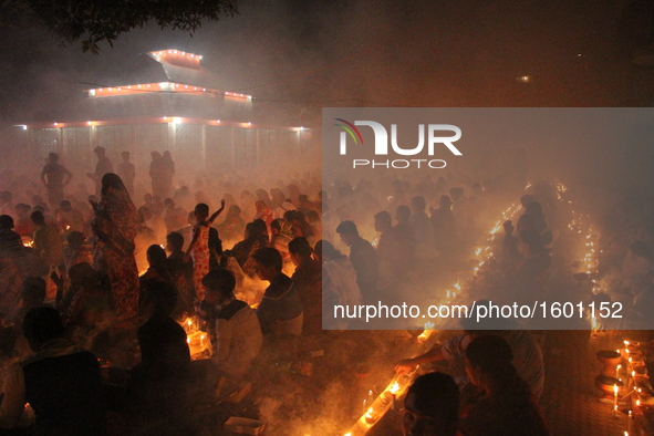 Bangladeshi Hindu devotees sit with candle light pray to God at Shri Shri Lokanath Brahmachari Ashram temple during the religious festival K...