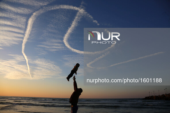 A Palestinian family on the beach in Gaza throw their young child in the air as the sun sets over the Mediterranean on January 21, 2016 in G...