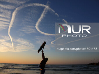 A Palestinian family on the beach in Gaza throw their young child in the air as the sun sets over the Mediterranean on January 21, 2016 in G...