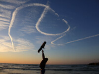 A Palestinian family on the beach in Gaza throw their young child in the air as the sun sets over the Mediterranean on January 21, 2016 in G...