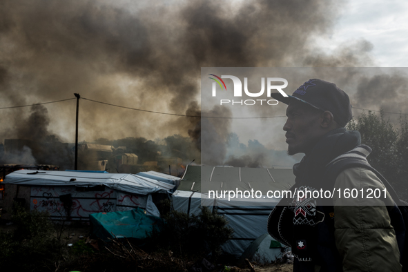 A Migrant looks in the in the Calais Jungle at the burning huts, on October 26, 2016. Huge fires destroyed a mayor part of the refugee camp...