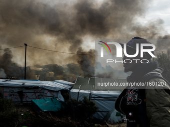 A Migrant looks in the in the Calais Jungle at the burning huts, on October 26, 2016. Huge fires destroyed a mayor part of the refugee camp...