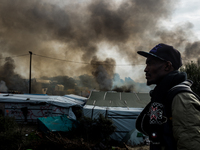 A Migrant looks in the in the Calais Jungle at the burning huts, on October 26, 2016. Huge fires destroyed a mayor part of the refugee camp...