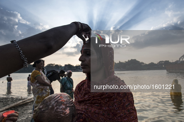 A woman putting tilak on her forehead after taking a holy dip into the river during the Chhath Puja festival in Kolkata, West Bengal on Devo...