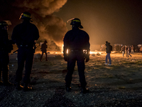 French riot police advance through tear gas and smoke from a fire to disperse migrants throwing stones and lighting fires at the Jungle migr...