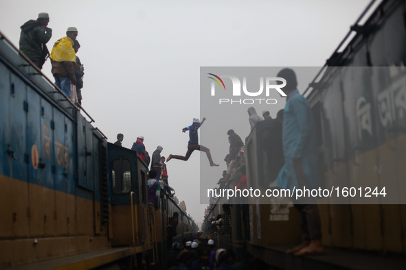 A boy jumps from one train to another train to ensure his seat as there are lots of people arrives today to attend final prayer of "Bishwa I...