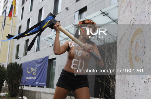 An girl from femenist movement "FEMEN" with inscription on her naked body "Ukraine to EU"  beat a hammer on a fragment of the Berlin Wall ne...