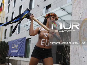 An girl from femenist movement "FEMEN" with inscription on her naked body "Ukraine to EU"  beat a hammer on a fragment of the Berlin Wall ne...