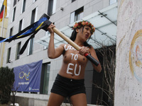 An girl from femenist movement "FEMEN" with inscription on her naked body "Ukraine to EU"  beat a hammer on a fragment of the Berlin Wall ne...