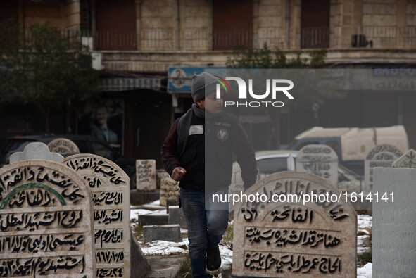 A Syrian boy walks through graves in a garden in the Hamidiyeh neighborhood of Aleppo city, Syria, on Dec. 21, 2016. Due to the intensity of...