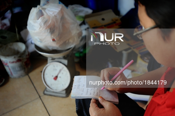 A woman records on Bank Sampah saving book. 
Bank Sampah (Garbage Bank) is a small business unit in neighborhood community operated by volun...