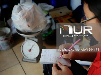 A woman records on Bank Sampah saving book. 
Bank Sampah (Garbage Bank) is a small business unit in neighborhood community operated by volun...