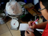 A woman records on Bank Sampah saving book. 
Bank Sampah (Garbage Bank) is a small business unit in neighborhood community operated by volun...