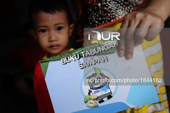 A woman shows Bank Sampah saving book.
Bank Sampah (Garbage Bank) is a small business unit in neighborhood community operated by volunteer h...