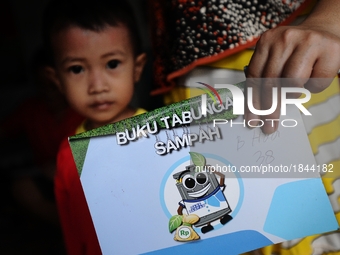 A woman shows Bank Sampah saving book.
Bank Sampah (Garbage Bank) is a small business unit in neighborhood community operated by volunteer h...