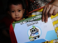 A woman shows Bank Sampah saving book.
Bank Sampah (Garbage Bank) is a small business unit in neighborhood community operated by volunteer h...