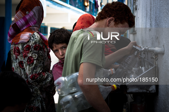 Children filling bottels with water at a make-shift refugee camp in Jabalya, Gaza on July 18th, 2014. The former school currently holds appr...