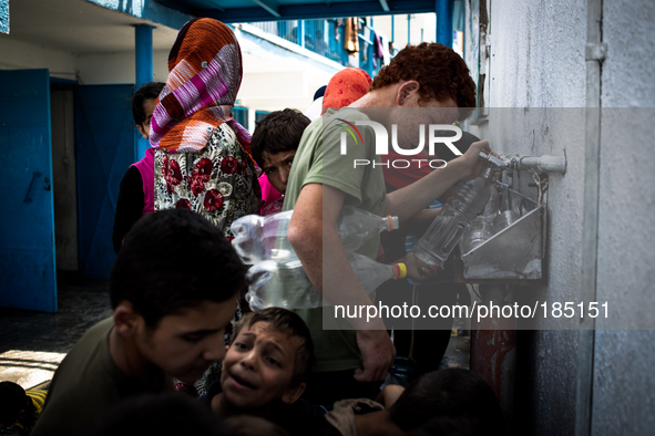 Children filling bottels with water at a make-shift refugee camp in Jabalya, Gaza on July 18th, 2014. The former school currently holds appr...