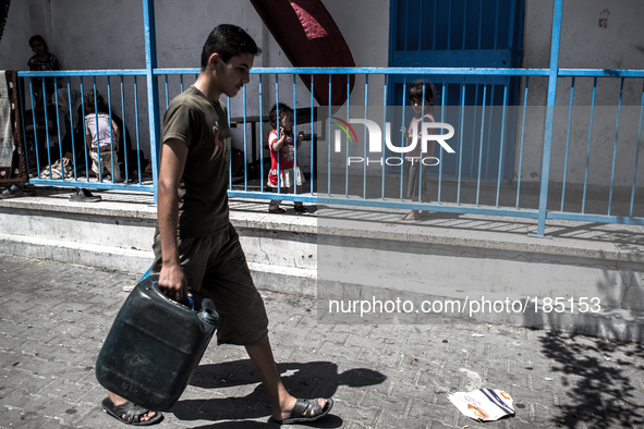 A boy walking to fill a canister with water at a make-shift refugee camp in Jabalya, Gaza on July 18th, 2014. The former school currently ho...