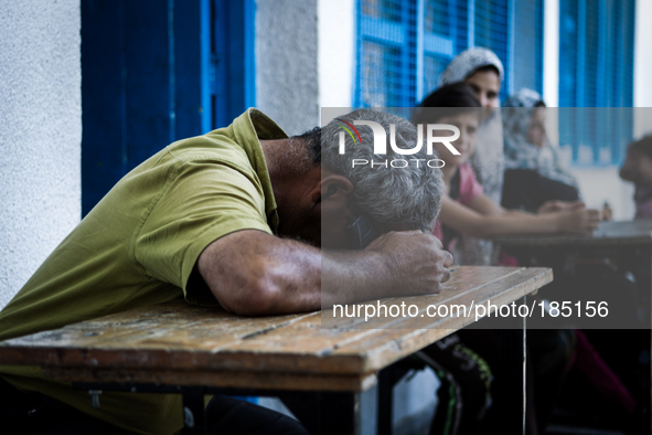 A man sleeping exhausted on a table at Jabalya, Gaza on July 18th, 2014. The former school currently holds approximately 3500 Palestinian. A...