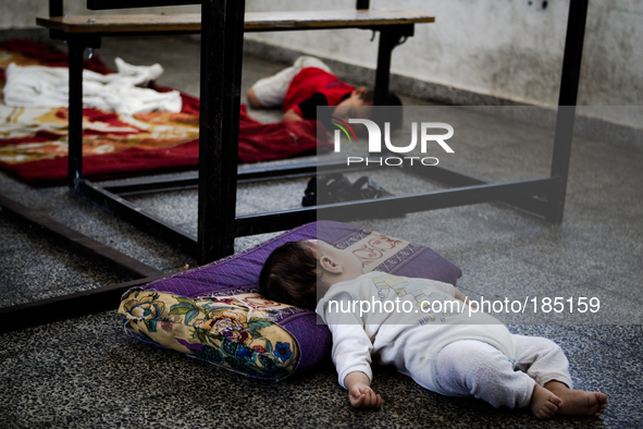 Two yound children sleeping on the floor of a make-shift refugee camp in Jabalya, Gaza on July 18th, 2014. The former school currently holds...