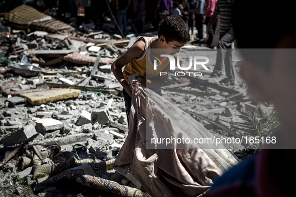 A young boy searches the remains of a home on Jaffa Street in Northern Gaza City for belongings minutes after the house was attacked by an I...