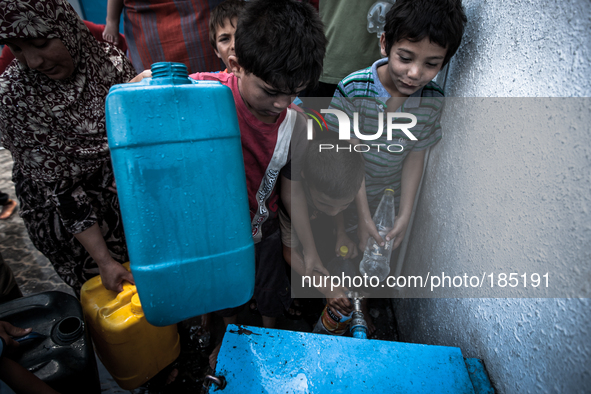 Children filling bottels with water at a make-shift refugee camp in Jabalya, Gaza on July 18th, 2014. The former school currently holds appr...