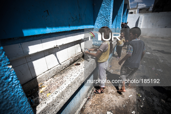 A girl is cleaning dishes at a make-shift refugee camp in Jabalya, Gaza on July 18th, 2014. The former school currently holds approximately...